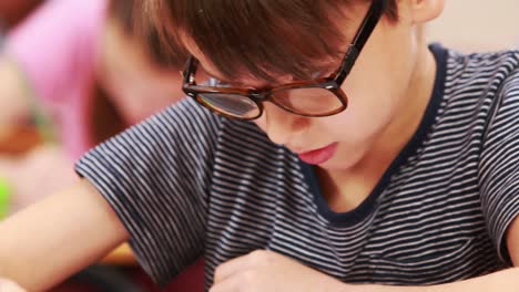 Cute-pupils-working-at-desks-in-classroom