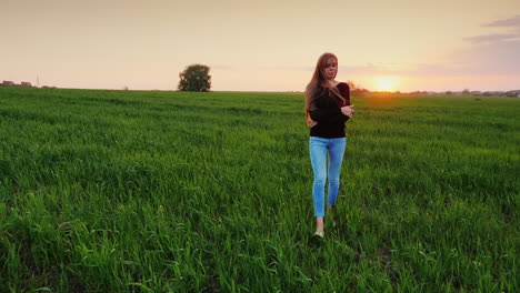 A-Young-Woman-With-Beautiful-Long-Hair-Walks-Along-The-Green-Field-1