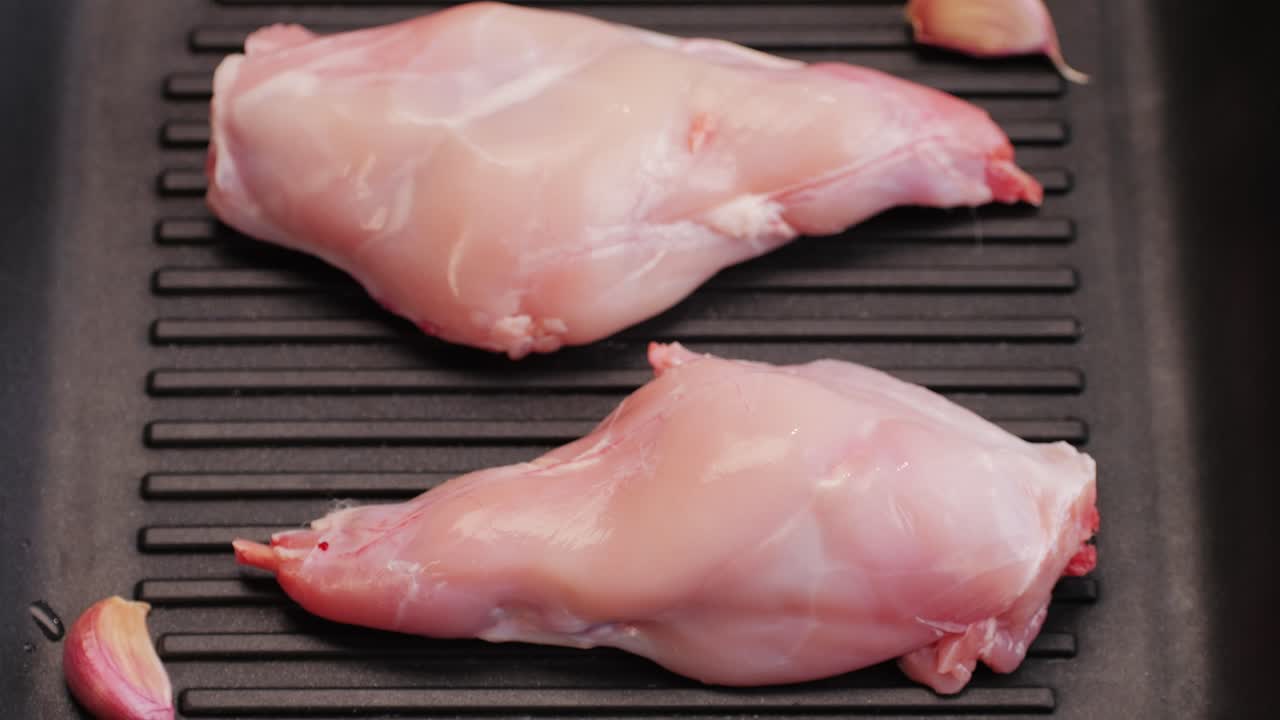Roasted rabbit legs in a grill pan, healthy diet meat close up, chef cooking rabbit on kitchen restaurant, Black background. Top view