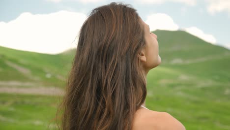 attractive woman looking out at the beautiful green hills and mountains of barcelonnette, france.