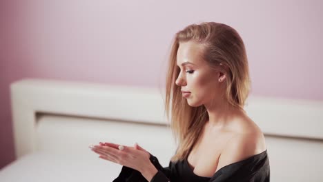 young-beautiful-girl-rubs-cream-with-collarbone-in-bedroom