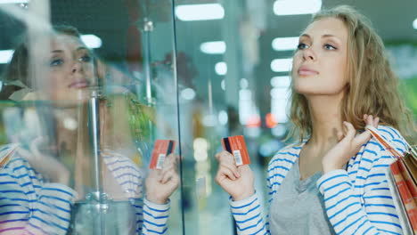 Attractive-Young-Woman-Looking-At-A-Glass-Display-Case-In-The-Store-The-Hands-Holding-The-Card-For-S