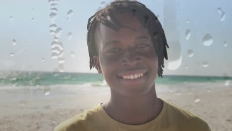 animación de un hombre afroamericano sonriente en una playa soleada sobre gotas