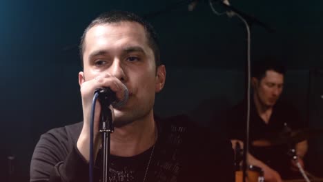 man singing into microphone with band playing in background