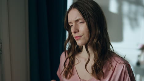 mujer sin sueño mirando la ventana sosteniendo el vidrio de primer plano. chica molesta con dolor de cabeza