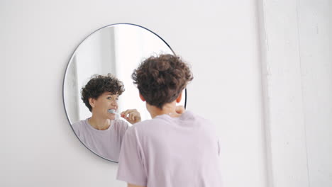 mujer cepillándose los dientes frente al espejo