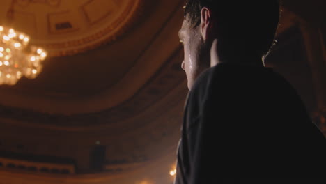 Close-up-shot-of-tired-ballet-male-dancer-standing-on-theater-stage-and-practicing-before-performance.-Sweat-flows-down-his-face.-Choreography-rehearsal.-Illuminated-theatrical-hall.-Classical-ballet.