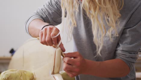 a caucasian male surfboard maker polishing a wooden surfboard edge