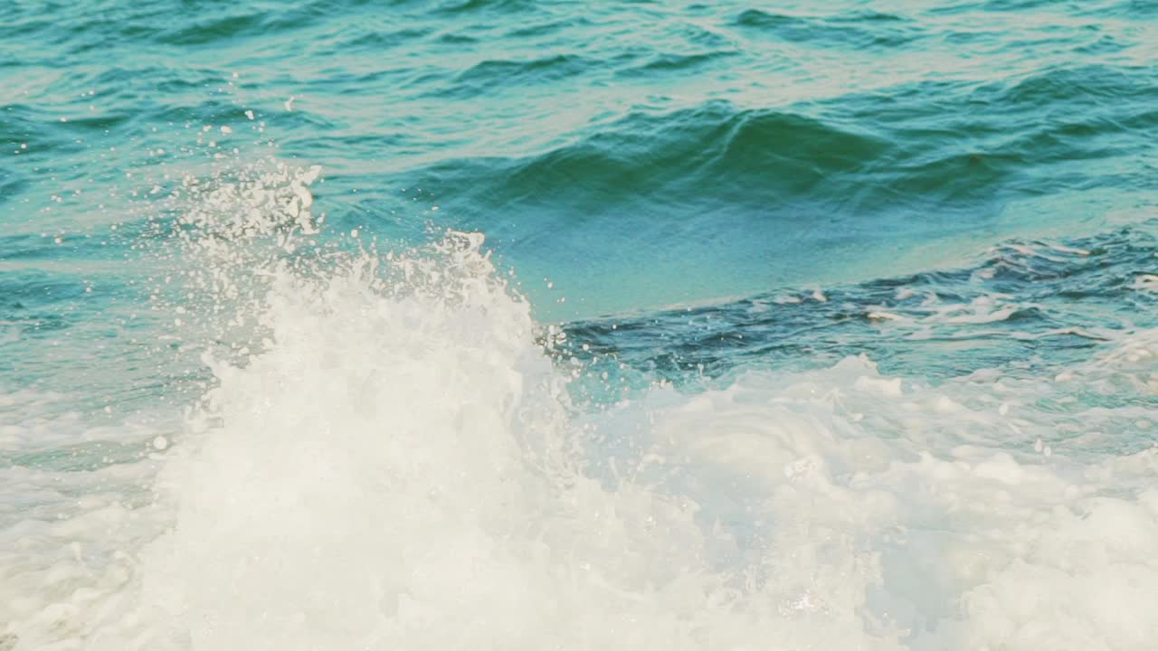 high sea waves of turquoise color are crashing on the rocks and turning into foam. Slow motion