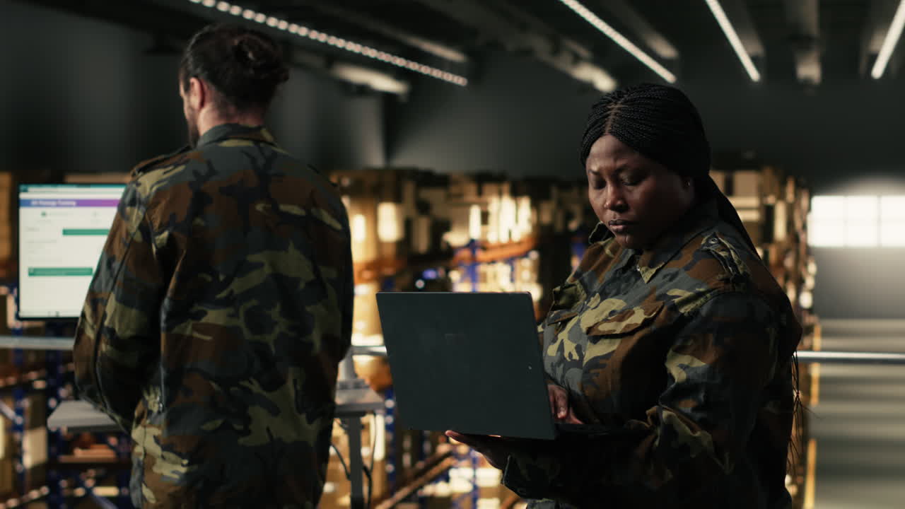 Donna afroamericana in divisa che lavora al laptop in magazzino