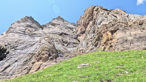 sheer rock face and jagged cliff above alpine meadow on a clear summer day in alpe devero, italian alps