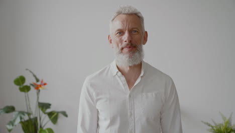 Senior-Man-With-Gray-Hair-And-White-Shirt-Looking-At-Camera-With-Serious-Expression