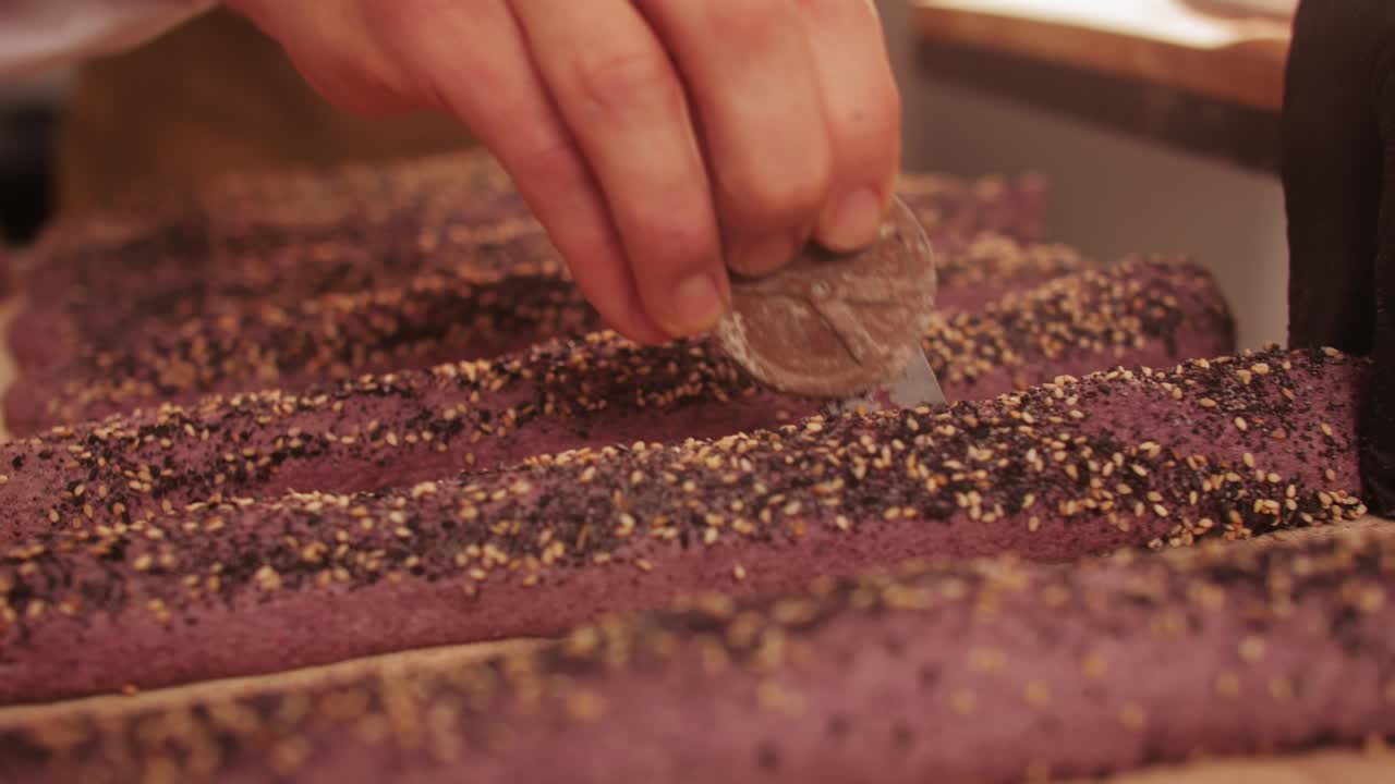 Bakery chef making different various of fresh Artesian buns and baguettes using traditional recipe close-up. Young man kneading dough. Artisan bread is making by skill bakers using natural and high-quality ingredients. Food with health and flavour benefits. Bakery shop and market