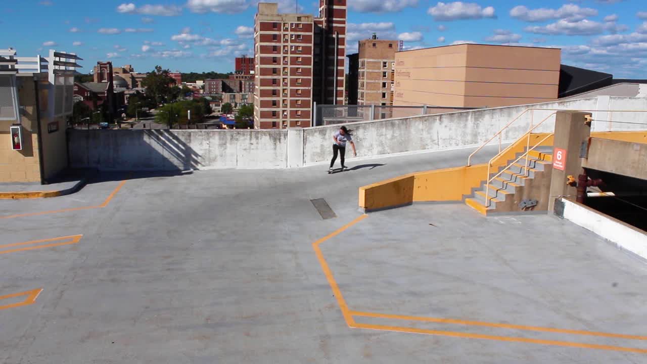 Chica patinando por un estacionamiento