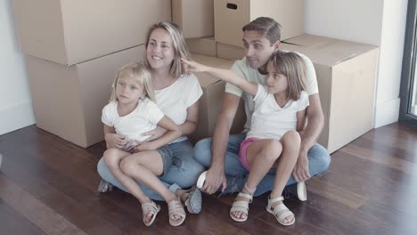 happy family couple and two daughters sitting on floor