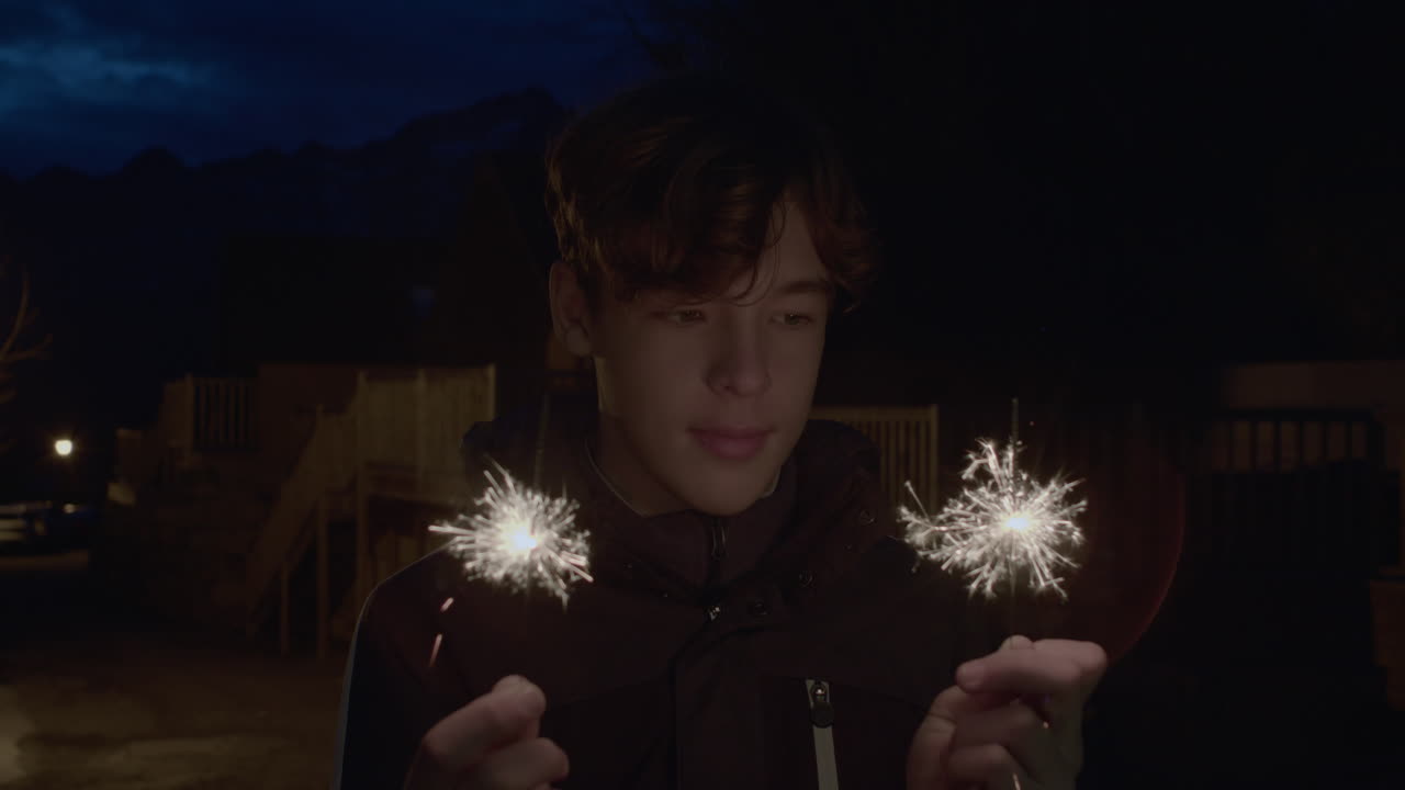 밤에 스파클러를 가진 십대 소년