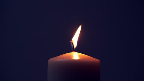 Single-big-yellow-candle-flame-lights-and-extinguish,-isolated-on-a-black-background