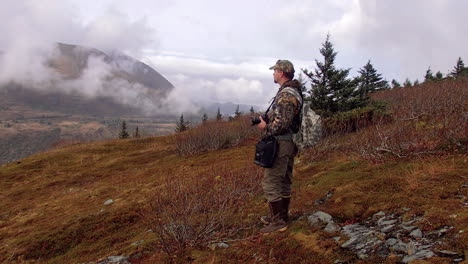 a nature and wildlife photographer hikes along the mountains of kodiak island alaska in preparation for a photoshoot