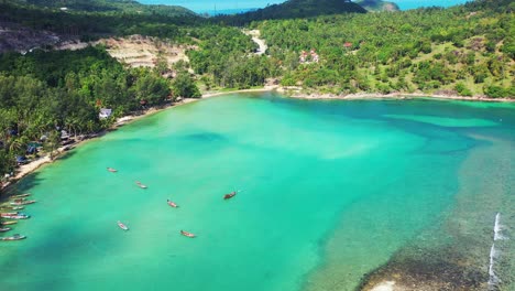 hermosa laguna de thaland con aguas tranquilas de color turquesa con barcos amarrados que revelan un gran istmo y un rompeolas natural.