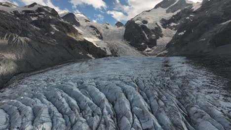 el avión no tripulado se retira para revelar la superficie del glaciar blanco entre las montañas, con picos nevados en el glaciar morteratsch, val morteratsch, suiza