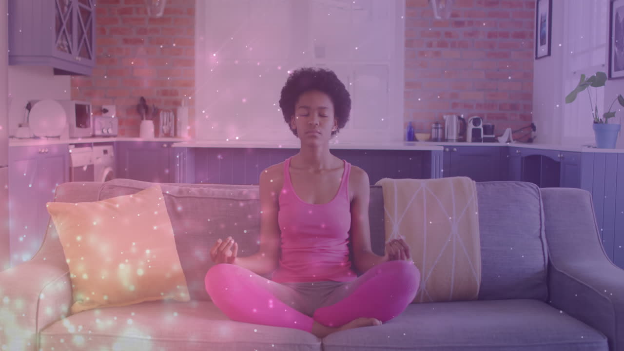 animación de puntos de luz sobre una mujer afroamericana practicando yoga y meditando en casa