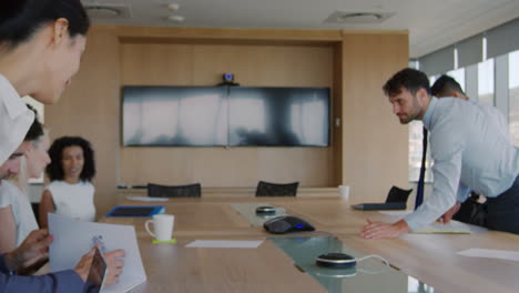 businessman hands out document at meeting around board table