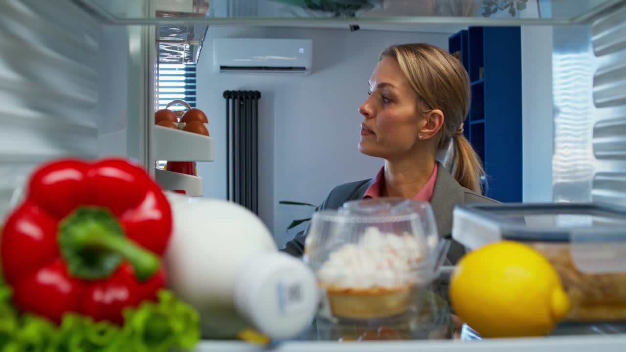 una mujer comprobando el refrigerador.