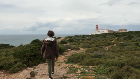 boy traveler walking to cape st vincent lighthouse in portugal