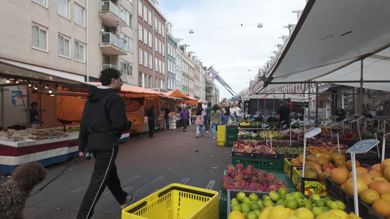De Pijp Market with fresh produce and colorful stalls, bustling atmosphere in a lively setting as visitors and tourists walk along center stretch
