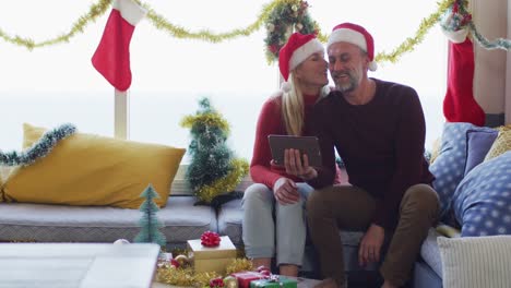 Happy-caucasian-mature-couple-making-video-call-in-room-full-of-christmas-decorations