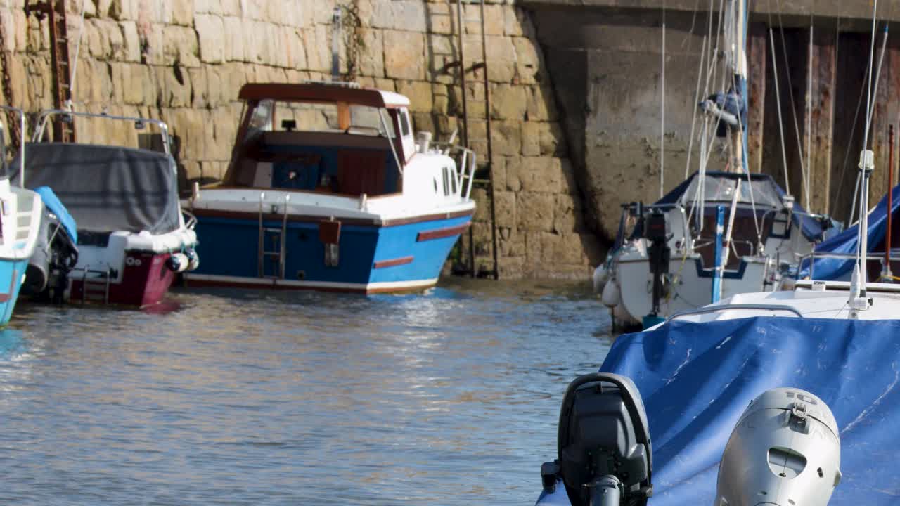 Moored motorboats gently floating in sunlit harbor, stone quay background, slight camera movement, daytime
