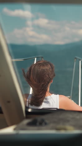 mujer descansa en la cubierta de proa del yate en una interesante vista de crucero oceánico desde la cabina. pasajeros viajan en un barco turístico rápido el fin de semana de verano. viaje acuático en barco