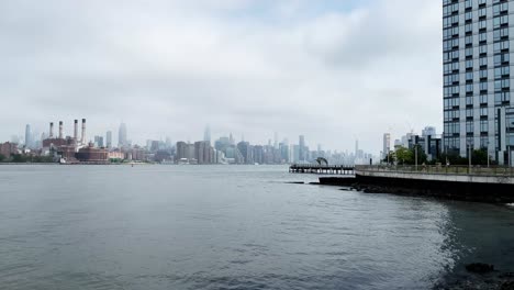 north williamsburg pier on a gloomy morning looking across the east river to manhattan skyline with the empire state building in clouds