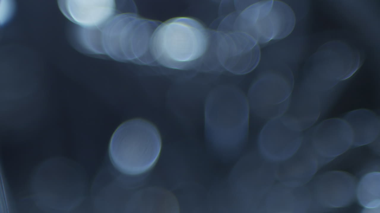 Luci bokeh blu in movimento su sfondo scuro.
