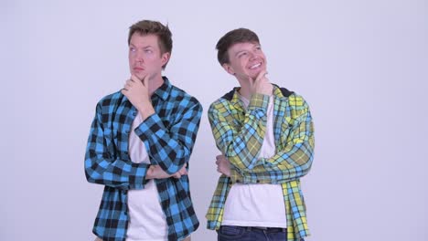 two happy young handsome men thinking together