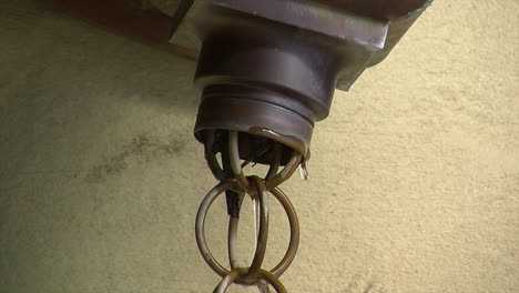 water drips out of copper downspout and down japanese rain chain