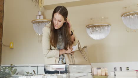 young caucasian woman with long hair holding bag, looking for jewelry