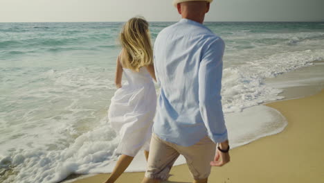 young couple running on sandy beach