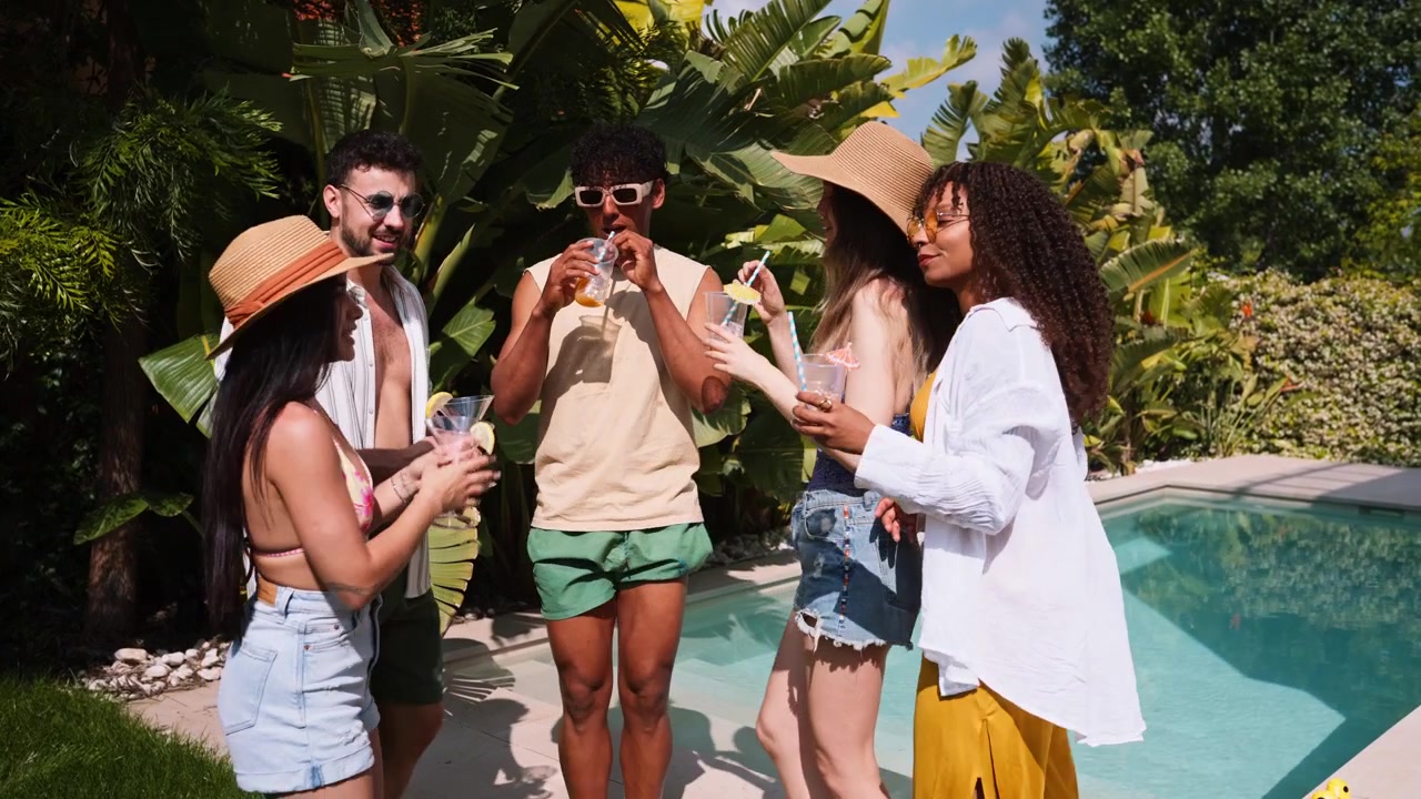 Gruppo di amici che socializzano e sorseggiano cocktail a bordo piscina