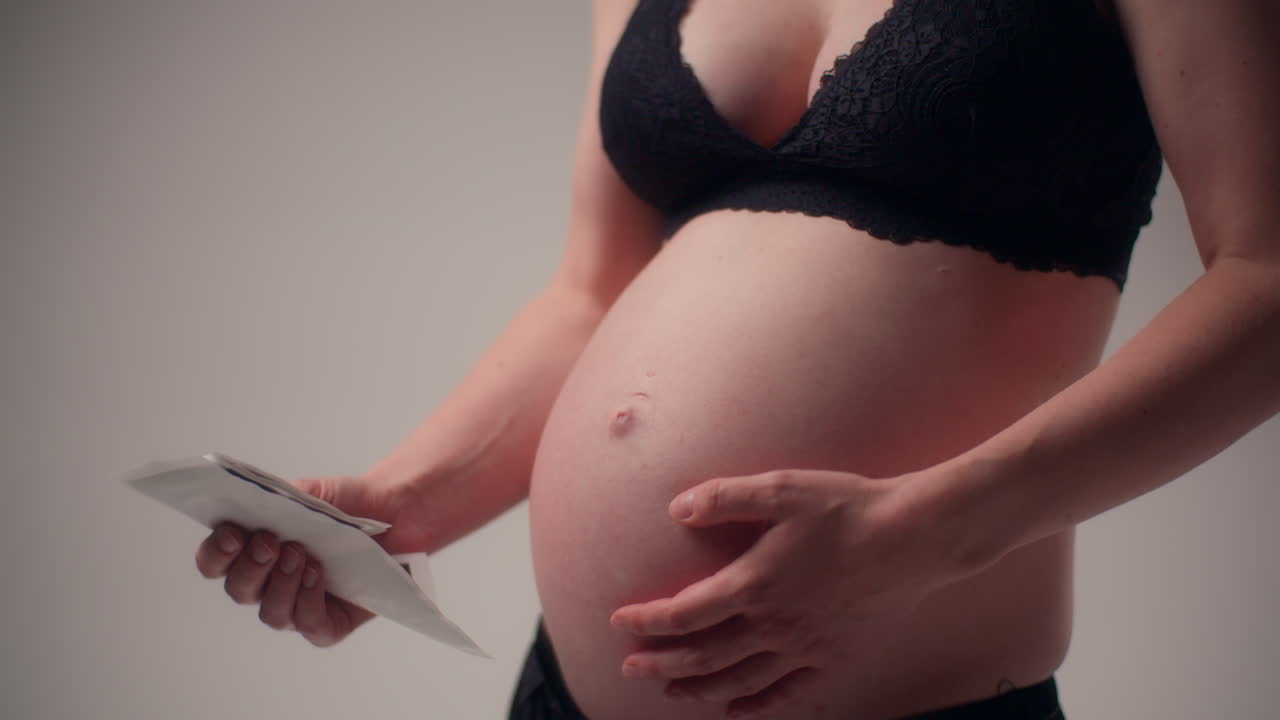 close up de una mujer embarazada sosteniendo fotos de ultrasonido a su corazón