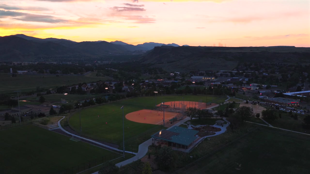 Skatepark do Complexo Esportivo Ulysses sob as luzes ao pôr do sol de verão, Cidade de Golden, vista aérea de drone das Montanhas Rochosas do Colorado, sopés da Front Range, Desfiladeiro Clear Creek, South Table Mountain, estacionamento, em direção ascendente.