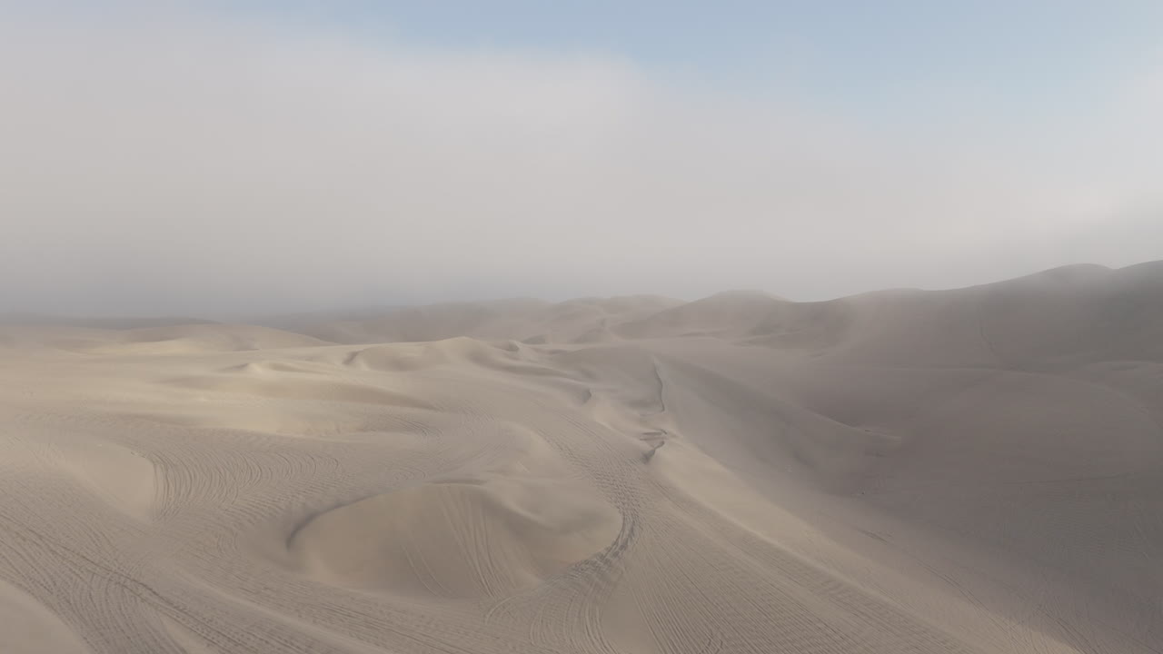 Drone shot above the dunes near Huacachina Peru on a cloudy day with some mist in LOG