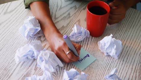 female executive writing on sticky notes while having coffee 4k