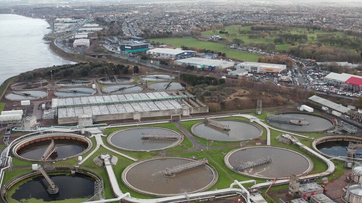 Panning aerial shot of a large sewage plant with a vast city in the background