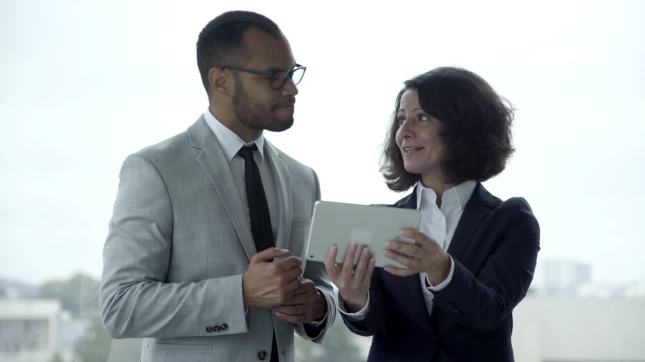Smiling people wearing formal wear using tablet