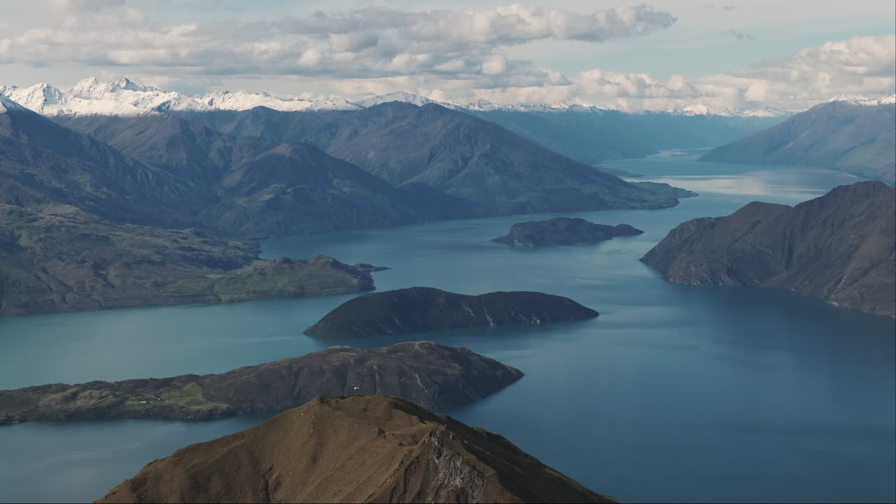 Ampia inquadratura di un elicottero su un bellissimo lago azzurro che si estende fino all'orizzonte circondato da montagne