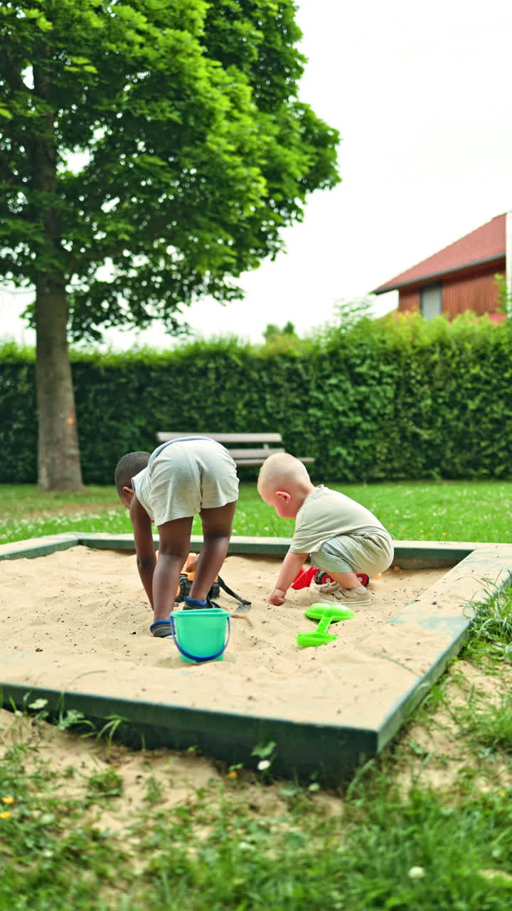 Children of different nationalities playing in the sandbox. A dark-skinned boy and a European boy playing together on the playground. Integration of children of different nationalities