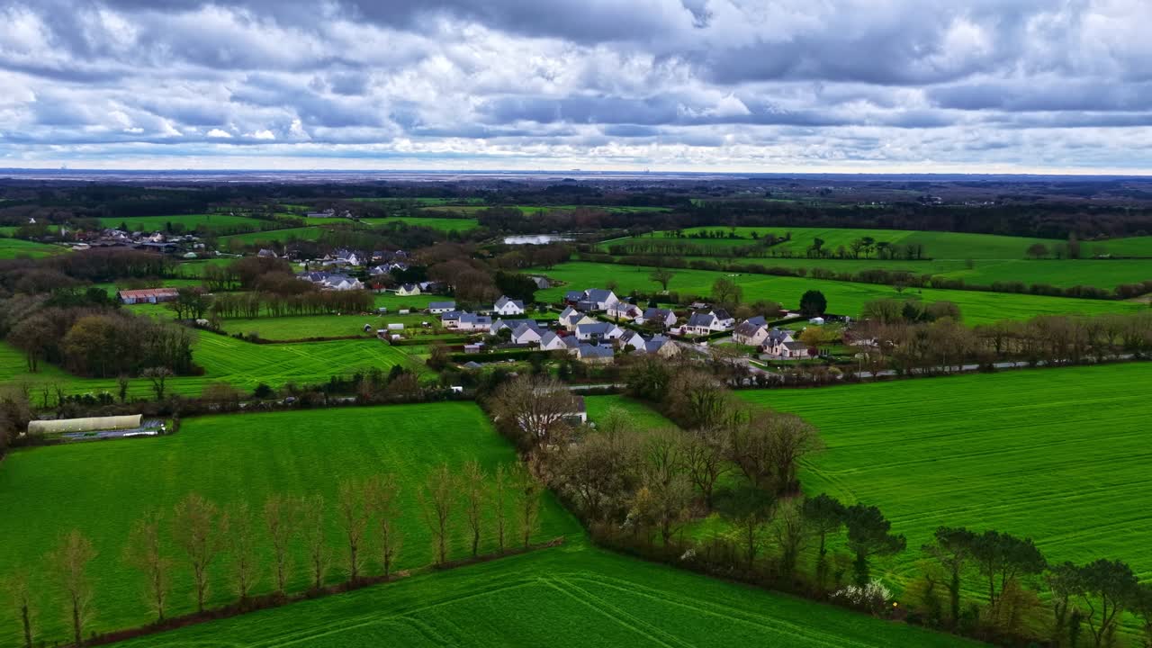 High panoramic aerial view shows a small village with the road running alongside it in a green rural setting