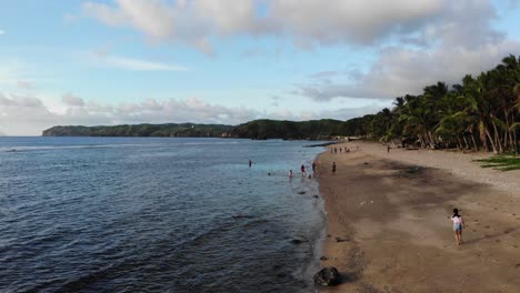 aerial shot along the ocean beach strip of the island province of batanes with locals and tourists having fun during summer