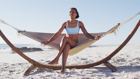 african american woman sitting on a hammock at the beach